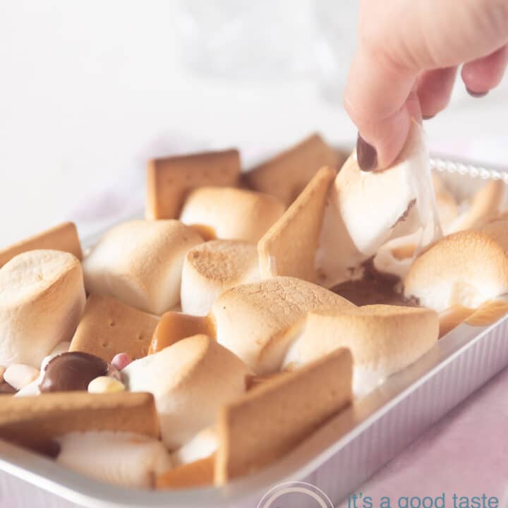 een hand pakt een s'more uit het aluminium bakje