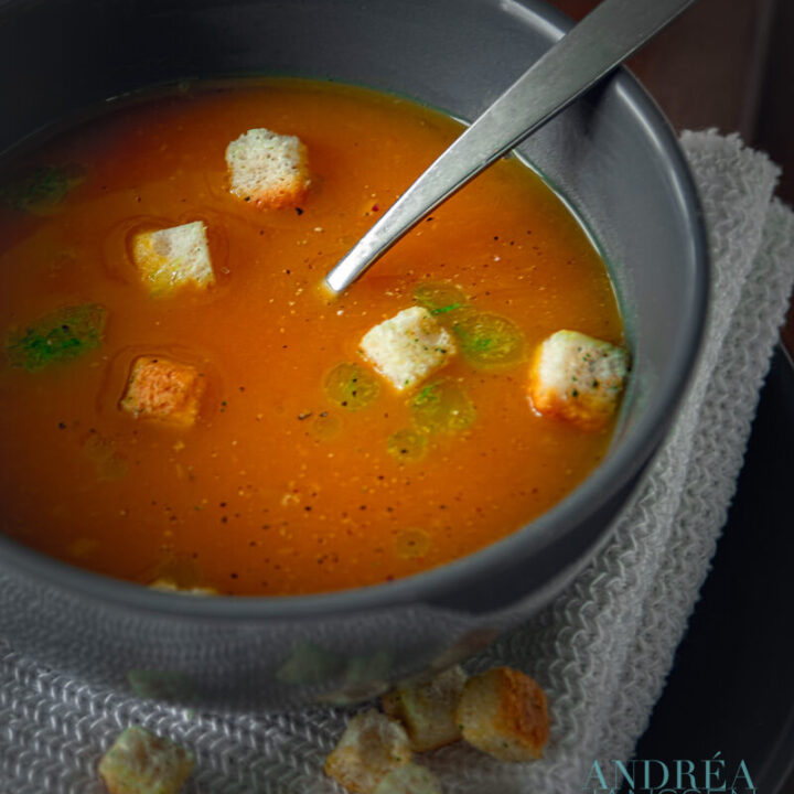 Een kom met pompoensoep, bieslook olie en croutons