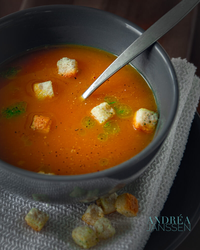 Een kom met pompoensoep, bieslook olie en croutons