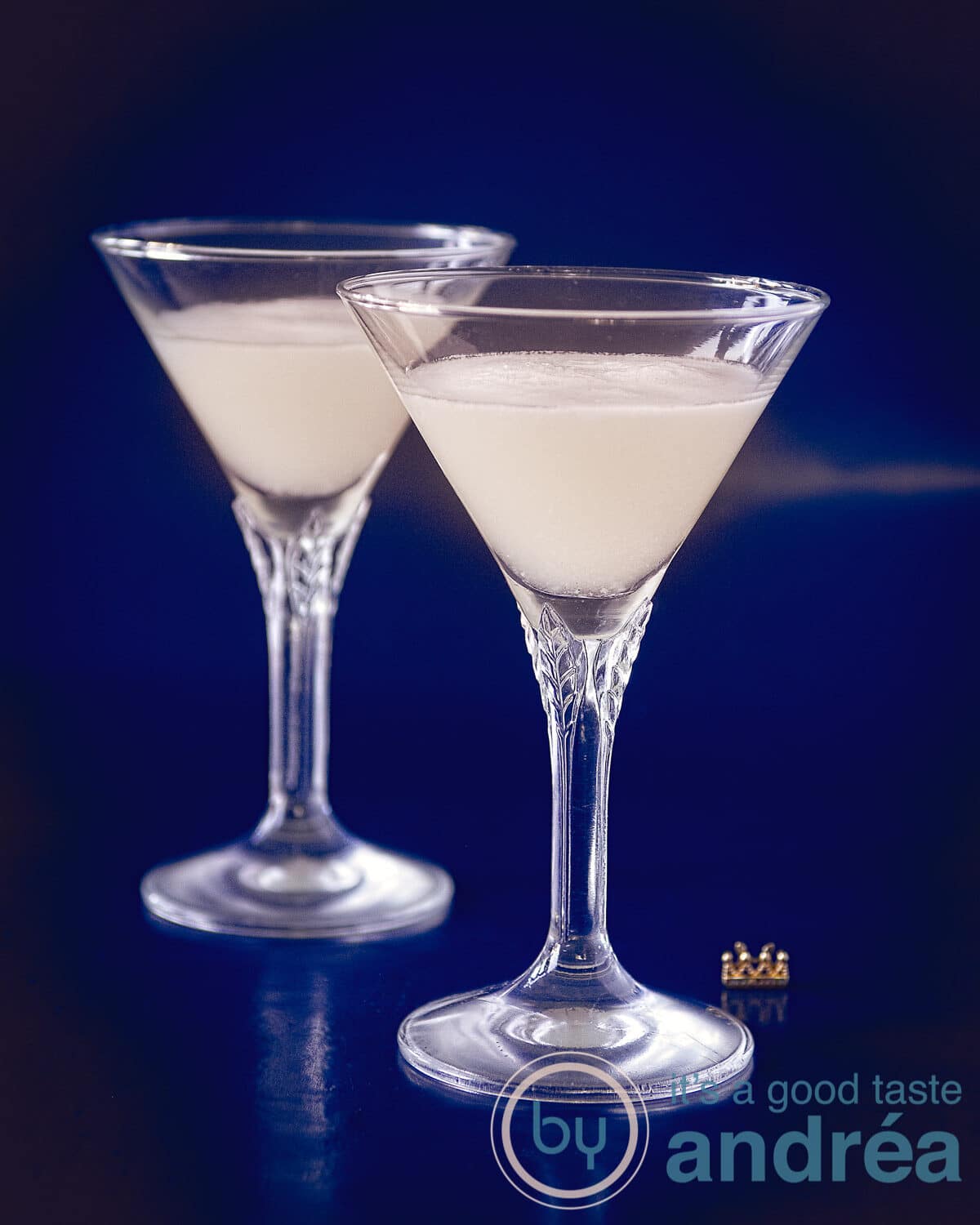 Twee kristallen glazen gevuld met sour sherry cream op een blauwe achtergrond.
