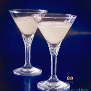 Twee kristallen glazen gevuld met sour sherry cream op een blauwe achtergrond.