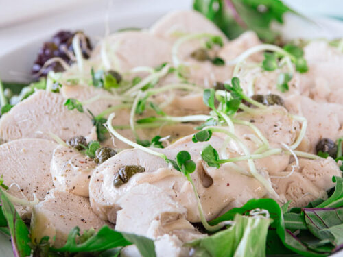 delicious turkey vitello tomato on a white plate with green salad