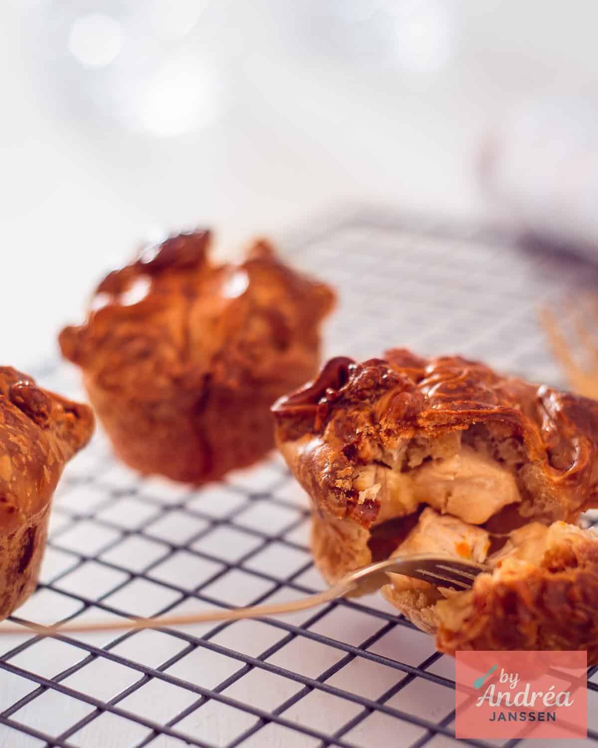 Mini kip-potpies op een bord, waarvan er één open is gesneden om de romige vulling te laten zien.