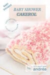 Een deel van een baby shower cake roll gevuld met slagroom, cake en aardbeienjam. Muisjes er omheen. Bovenin een tekstoverlay: baby shower cake roll