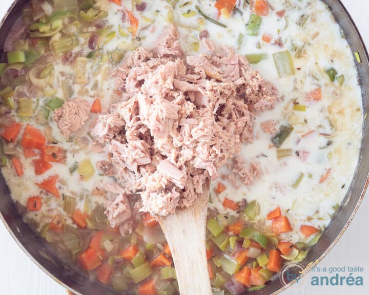 Aan een pan met groenten en saus wordt tonijn toegevogd