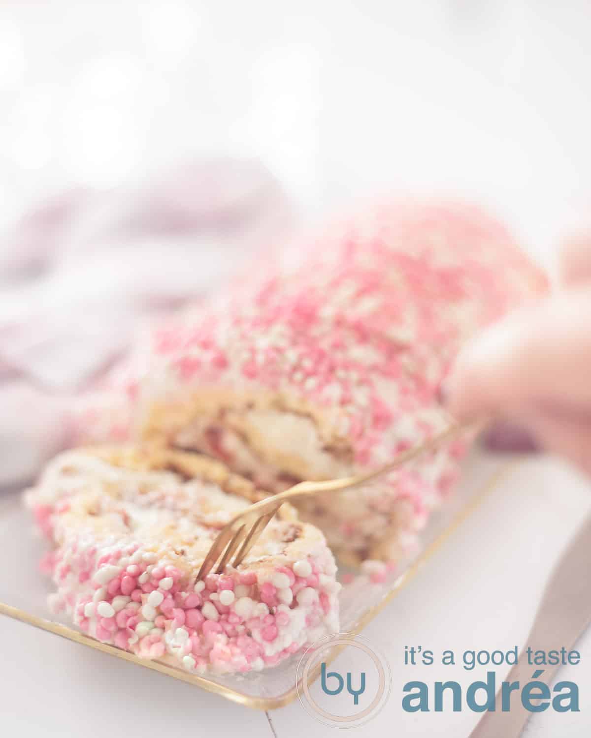 Een cakerol waarvan een plakje is afgesneden. Een gouden vork neemt een hapje. Op een witte ondergrond