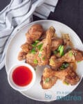 een bord met kip drumsticks in soja saus en een kommetje met chilisaus