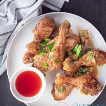 een bord met kip drumsticks in soja saus en een kommetje met chilisaus