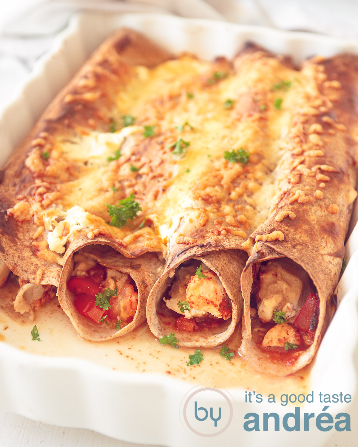 a white casserole dish with four chicken enchilada wraps au gratin.