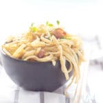 bami goreng met ei en ham in een grijze kom op een wit met grijs gestreepte theedoek