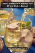 Een glas gember ijsthee met citroen en munt, gevuld met ijsblokjes en verse gemberplakjes, terwijl er ijsthee wordt ingeschonken vanuit een glazen karaf op een blauwe achtergrond.