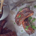 bakpapier met daarop stukjes Zoete spareribs met BBQ saus