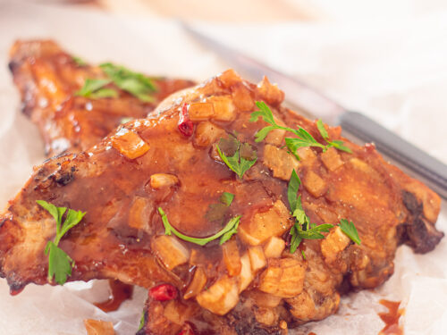 bakpapier met daarop stukjes Zoete spareribs met BBQ saus