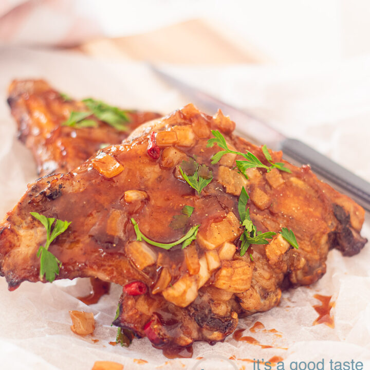 bakpapier met daarop stukjes Zoete spareribs met BBQ saus