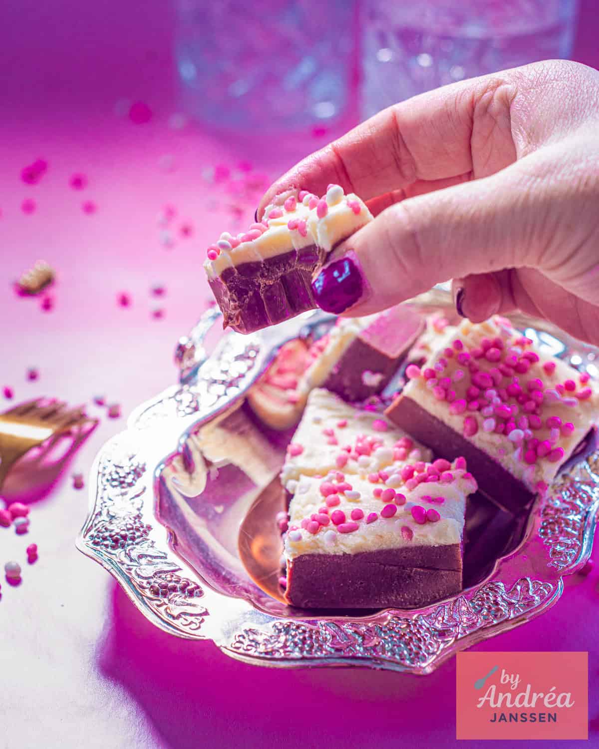 Een hand pakt een red velvet fudge van een zilveren schaal