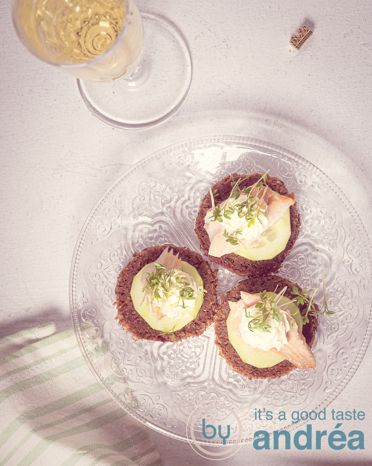 3 hapjes op een bord met gerookte forel een theedoek en champagne