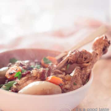 een witte pan met coq au vin op een houten plank