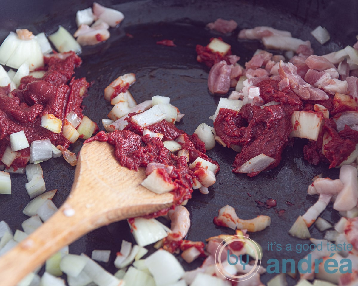 een koekenpan met ui, tomatenpuree en spekjes