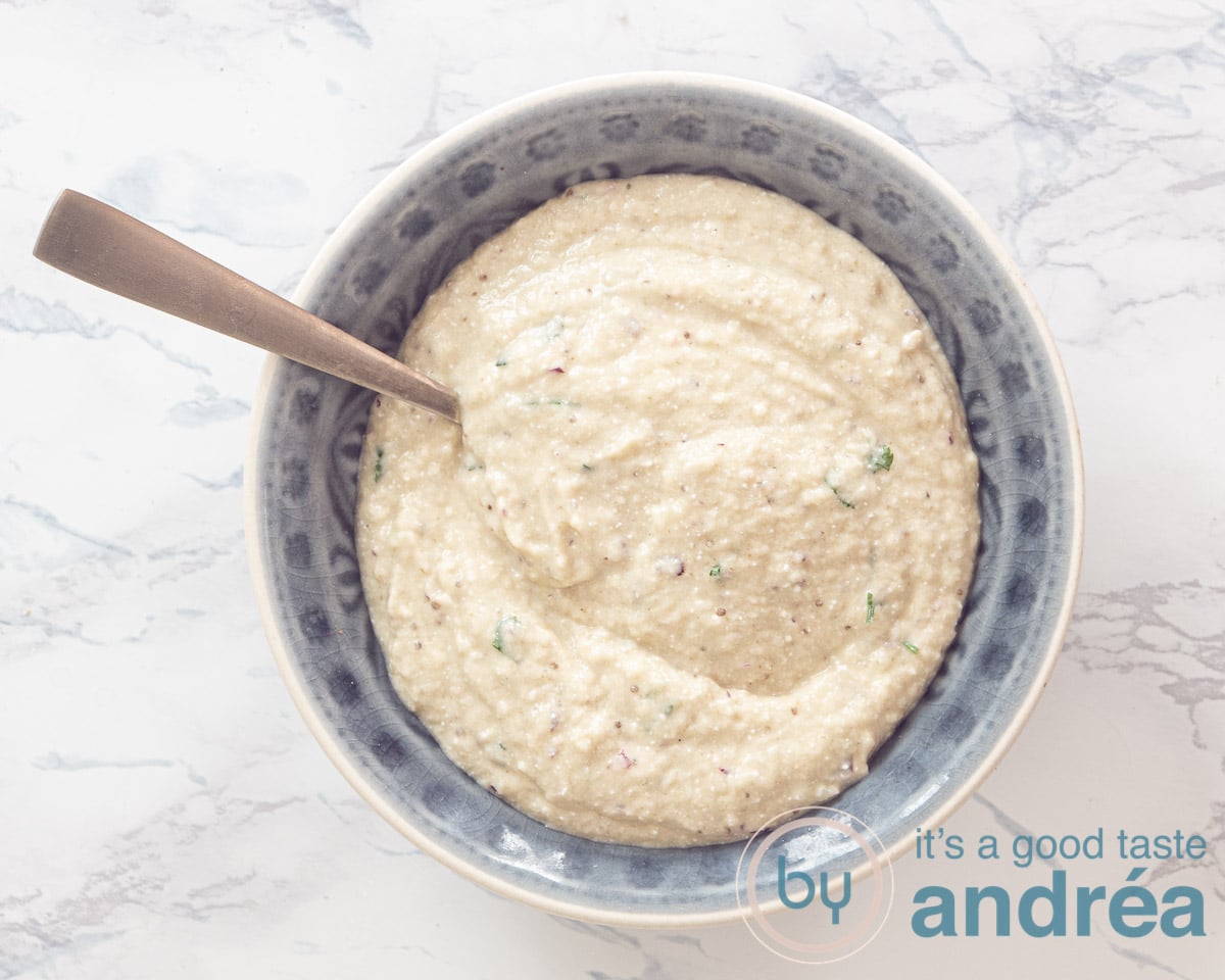 Een schaaltje met aubergine dip en ene gouden vork erin