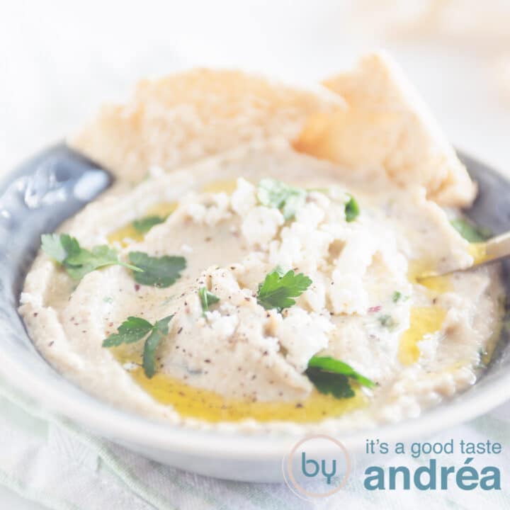 een vierkante foto met een grijs schaaltje, melitzanosalata met peterselie en olijfolie, puntjes pita brood