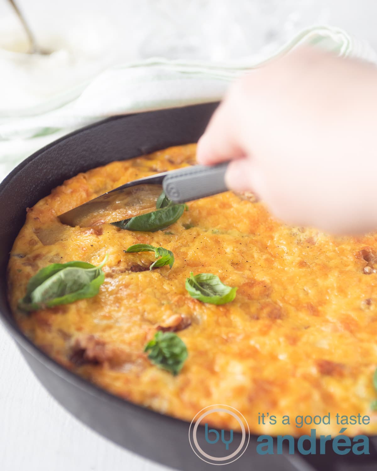 Een tortilla in een gietijzeren pan. Een mes snijdt een stuk uit de omelet.