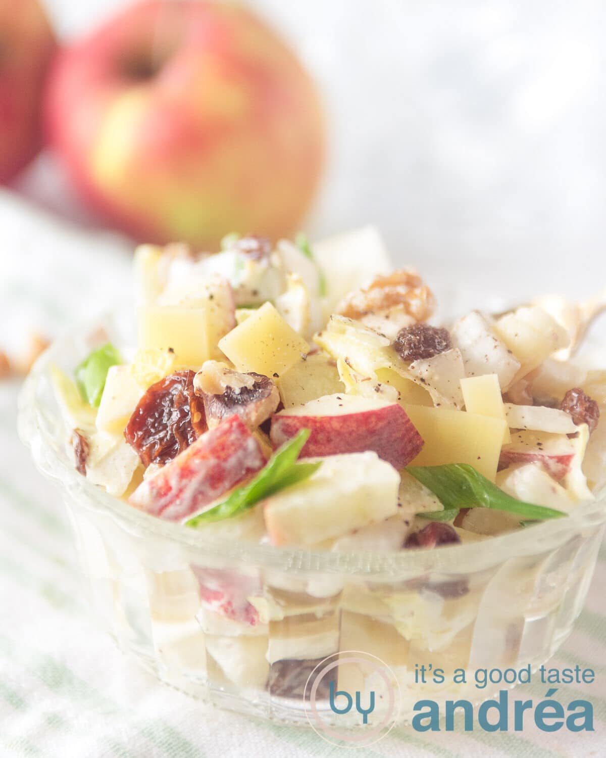 Driekwart glazen kommetje gevuld met een salade van witlof, appel en rozijnen