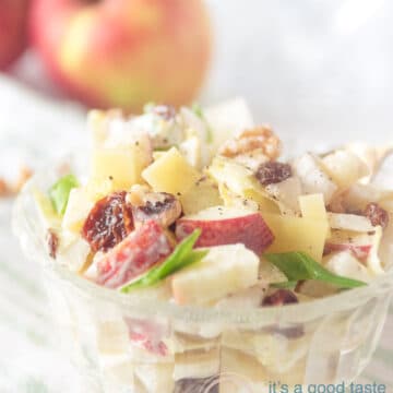 Driekwart glazen kommetje gevuld met een salade van witlof, appel en rozijnen