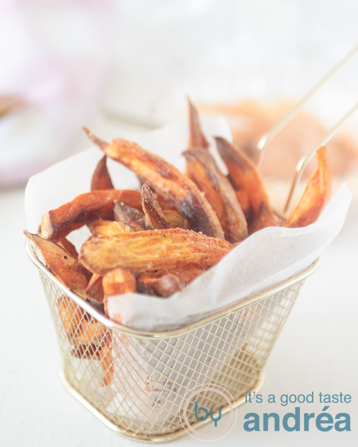 In het midden een gouden frietbakje waarin een bakpapier is gevouwen met friet van zoete aardappels erin