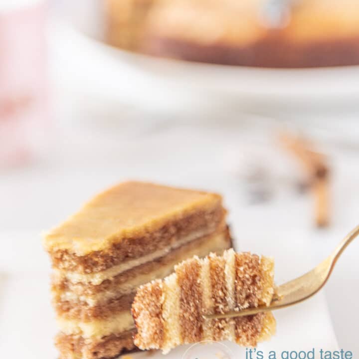 Een vork die een hapje spekkoek vastheeft. Op de achtergrond een plakje spekkoek en de hele spekkoek