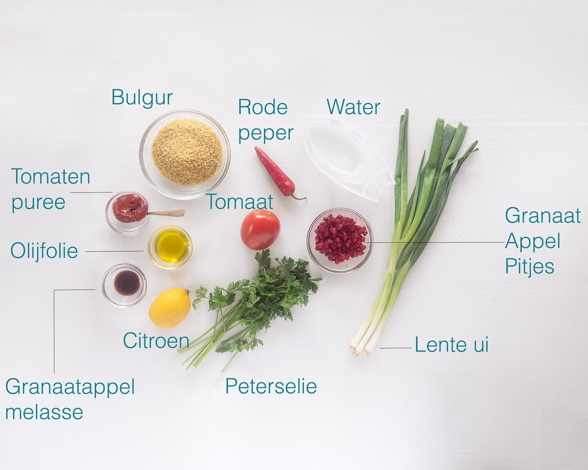 Ingredienten voor Kisir een Turkse Bulgur salade op een witte ondergrond