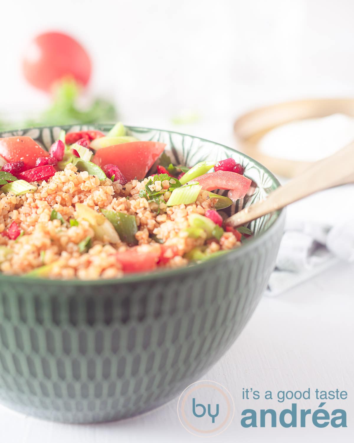 Een groene kom met Turkse Bulgur salade met granaatappel en tomaat