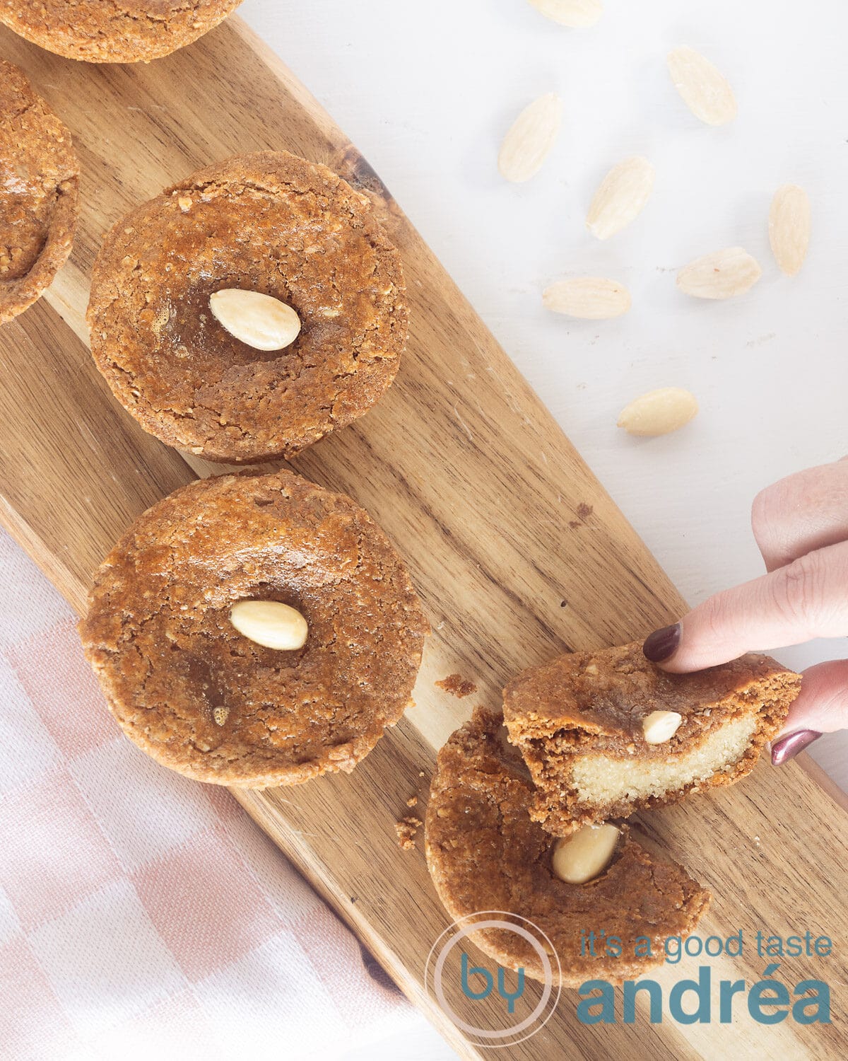 Nederlandse met amandel gevulde kruidenkoekjes op een houten bord. Een hand duurt een helft.