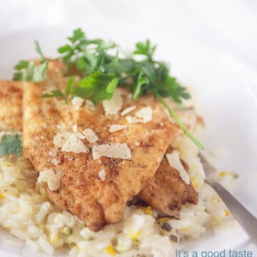 Foto van een wit bord met een gouden lepel. Het bord is gevuld met risotto met courgette en kaas. Daarboven op liggen twee moten gebakken kabeljauw