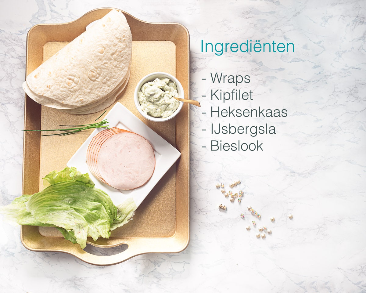 Ingredienten koude kip wraps met ijsbergsla en heksenkaas op een marmeren achtergrond. Een text overlay beschrijft de foto.