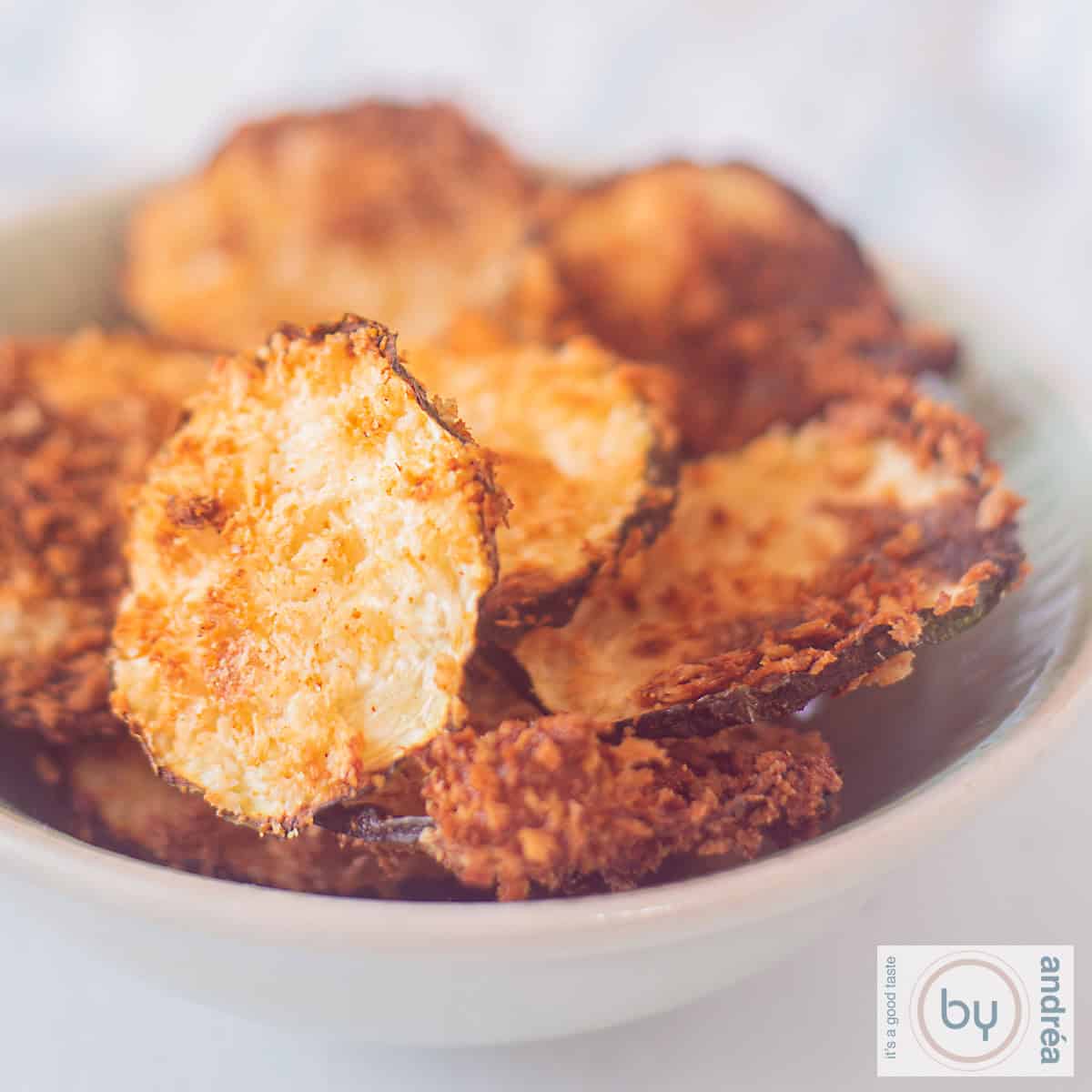 Een vierkante foto met courgette chips met Parmezaanse kaas en kruiden