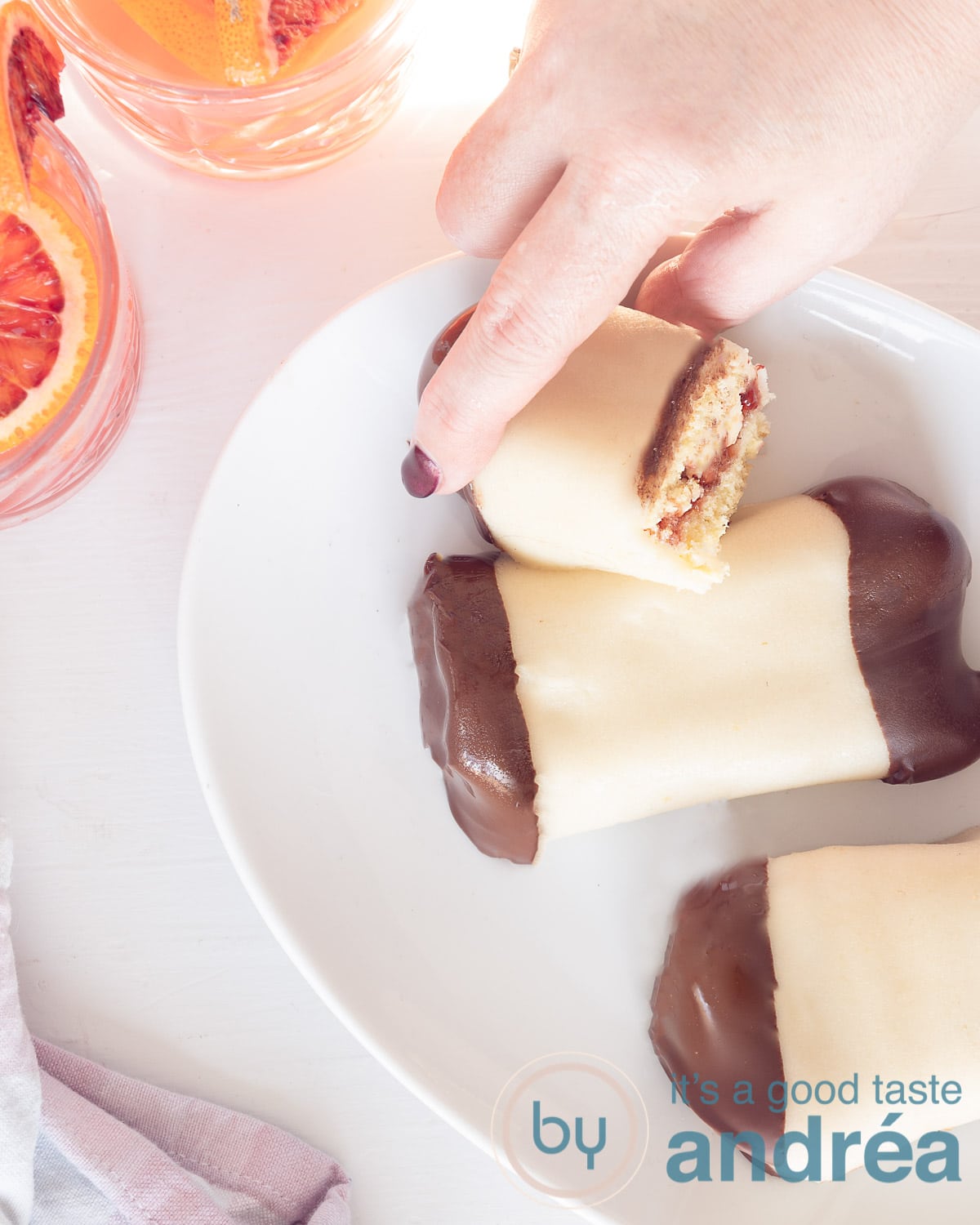 Een foto van bovenaf van een cake met marsepein en chocolade omhulsel gevuld met jam en creme. Een witte ondergrond.