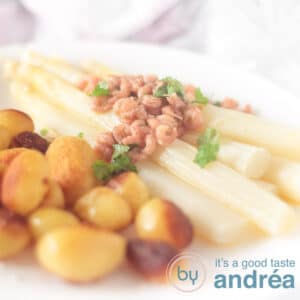 Een vierkante foto van een wit bord met krieltjes asperges,garnalen botersaus