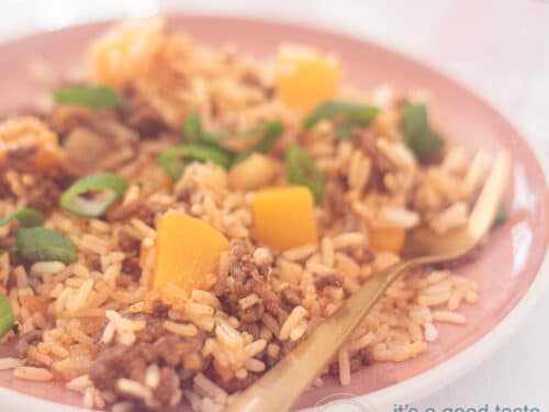 Een vierkante foto met rijst, gehakt en perzik op een roze bord