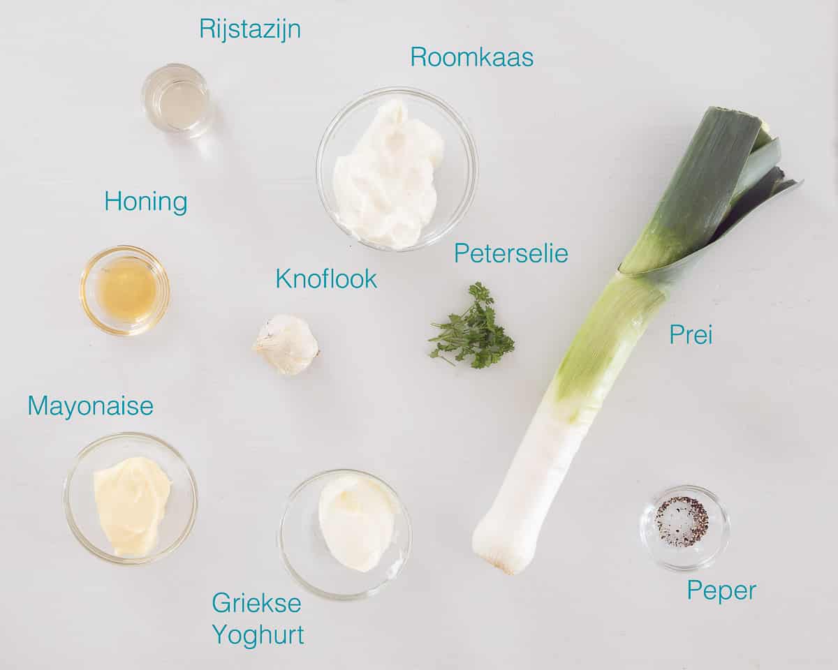 Individueel gelabelde ingrediënten om Prei roomkaas dip te maken op een witte ondergrond verspreidt