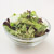 Groene gemengde salade in een glazen schaaltje op een witte ondergrond