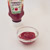 Kethcup in een glazen schaaltje op een witte ondergrond. Een fles ketchup staat erachter
