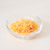 Grated Cheddar cheese in a glass bowl on a white background