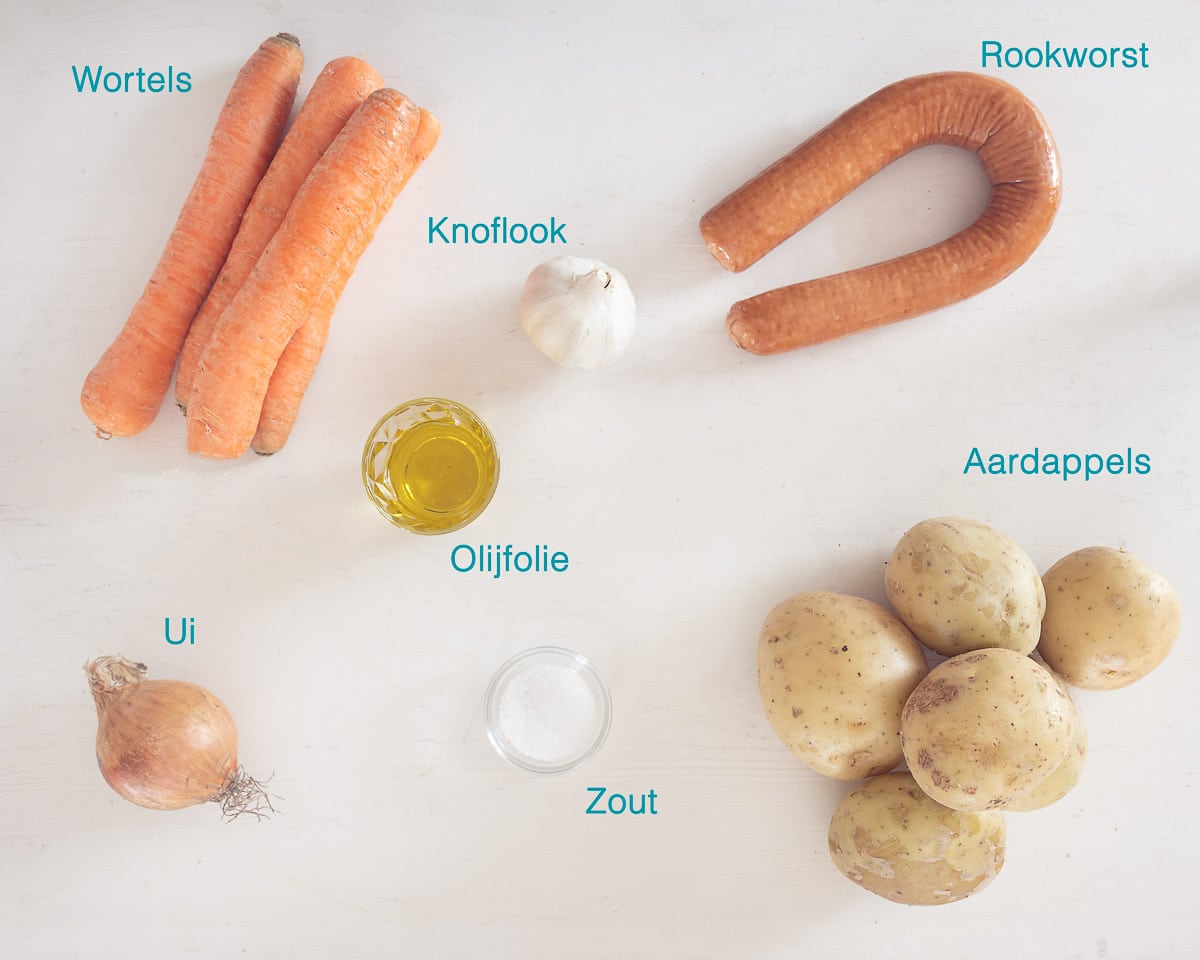 Ingrediënten Traybake van Aardappel met Rookworst en Wortel, individueel gelabeld op een witte ondergrond.