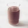 Een glas gevuld met chocolade vla op een witte achtergrond