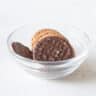 Een glazen schaaltje gevuld met chocoladekoekjes op een witte ondergrond