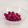 Een glazen schaaltje met cranberries op een witte ondergrond