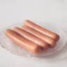 four frankfurters on a glass plate on a white background