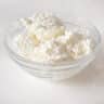 Cottage cheese / huttenkase in een glazen schaaltje op een witte ondergrond