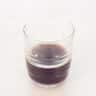 A glass filled with espresso on a white background