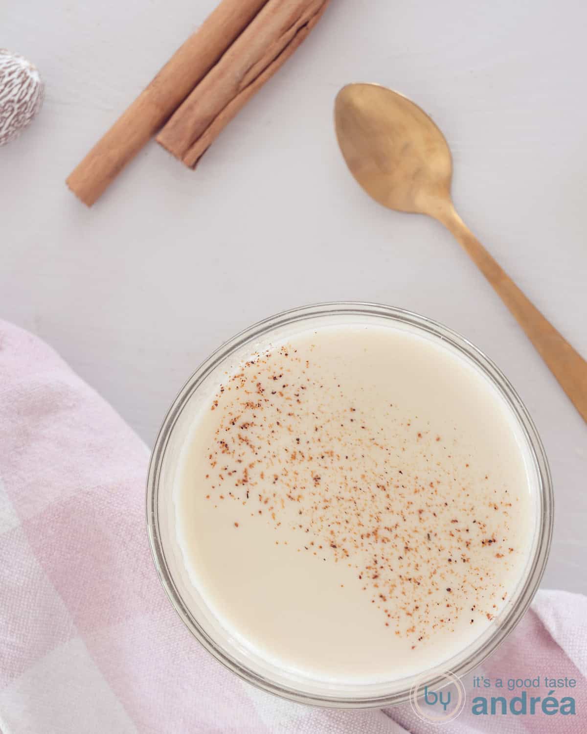 Een foto van bovenaf van Chai The op een witte ondergrond. Kaneel, nootmuskaat en een gouden lepel liggen erboven.